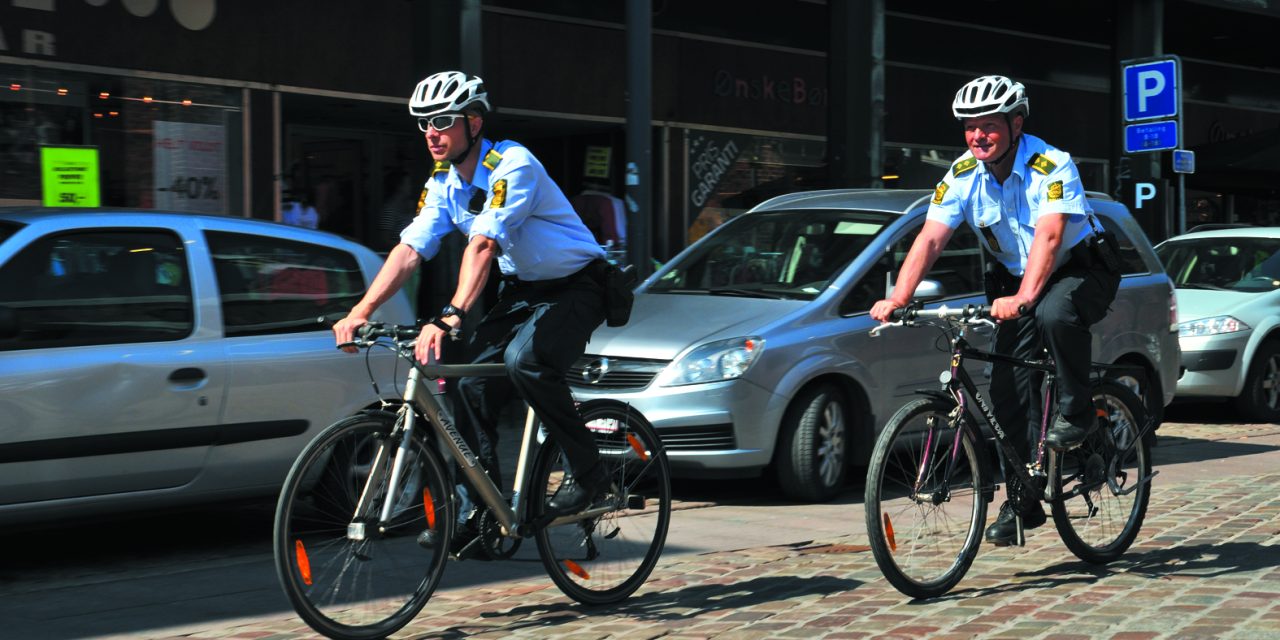 Politi på cykel så mand ryge det forkerte på en bænk